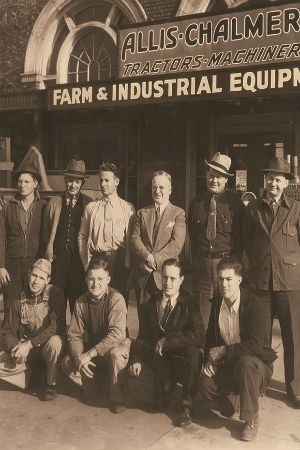 EC Papé en 1938, parado junto a colegas frente a una tienda de Farm & Industrial Equipment que actualmente es Oregon Electric Station